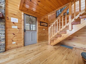 A wooden interior with a staircase, a door, and a stone wall. - Secluded | Pigeon Forge | Pool Table | Arcade | Pet Friendly | Hot Tub | WiFi (PIGEON FORGE)