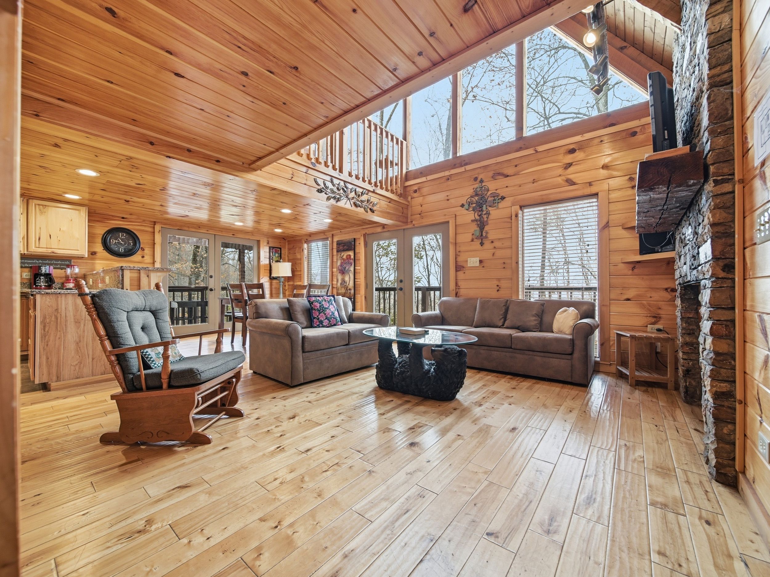 A spacious living room with wooden floors, a large sofa, a coffee table, and a fireplace.