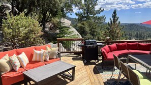 A deck with a red sofa, a small table, and a grill.