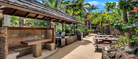 An outdoor patio with a grill, seating, and a covered area with a stone wall.