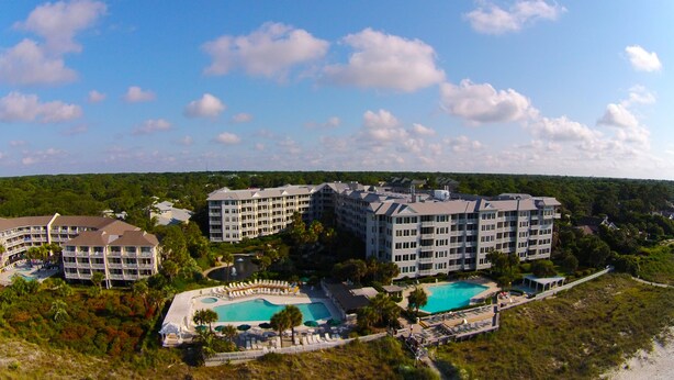 A resort with multiple buildings, a central pool, and a smaller pool surrounded by lounge areas.