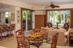 A spacious living area with a glass dining table, wooden chairs, and a sofa.