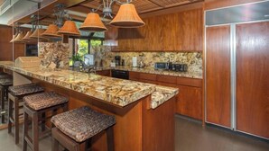 Une cuisine moderne dotée d’un plan de travail en marbre, de meubles en bois et d’un îlot central intégré avec des tabourets de bar.