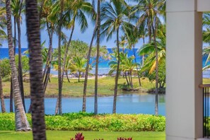 A view of a tropical landscape with palm trees and a body of water.