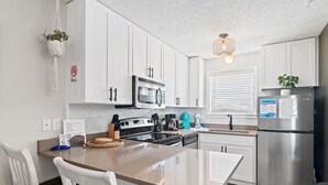 Una cocina moderna con armarios blancos, electrodomésticos de acero inoxidable y una isla central con asientos.