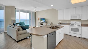 A modern kitchen with a built-in dishwasher, white cabinets, and a large island. - Lighthouse 1404 by Liquid Life (Gulf Shores)