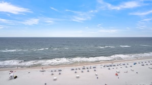 A beach with white sand, ocean waves, and clear blue sky. - Lighthouse 1404 by Liquid Life (Gulf Shores)