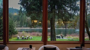 Une pièce dotée de grandes fenêtres donnant sur un lac, avec une table à manger et une chaise.