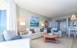 A modern living room with a sofa, armchairs, a coffee table, and a dining area. - Beachfront Condo with Views from Both Bedrooms. Includes Beach Service (Destin)