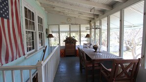 Un portico coperto con un tavolo, sedie, una bandiera e una sveglia.