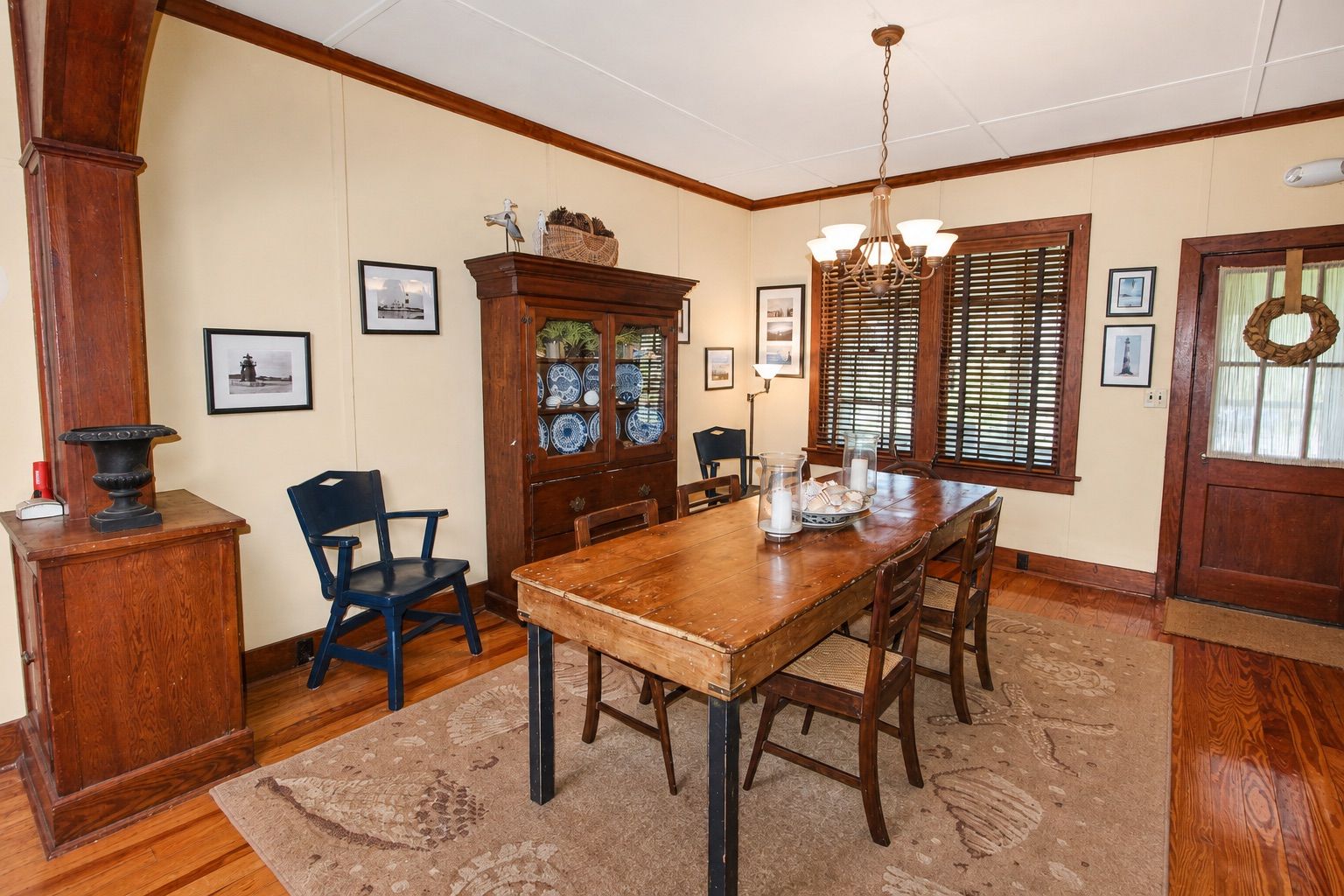 Comedor con una mesa de madera, sillas, un candelabro y una vitrina de vidrio.