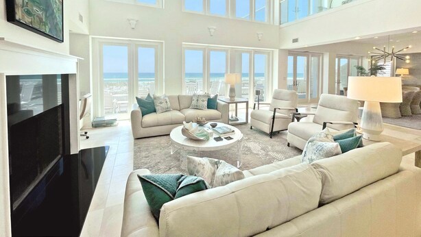 Ein geräumiges Wohnzimmer mit großem Fenster zum Meer, einem Flachbildfernseher und einer hohen Decke mit Oberlicht.