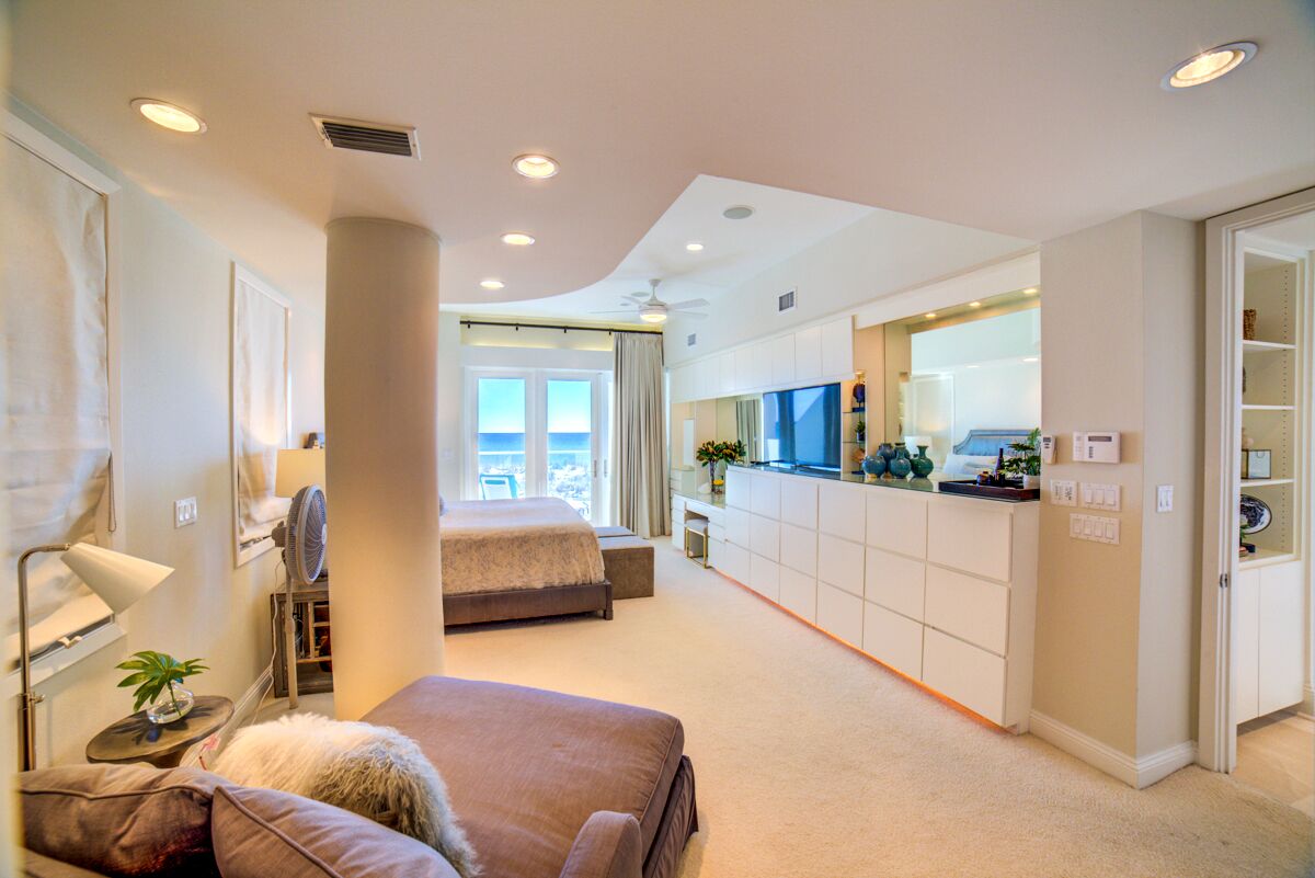 A modern hotel room with a large bed, a desk, and a kitchenette.