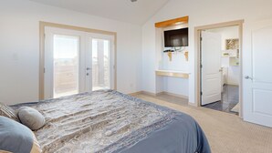 A bedroom with a bed, a ceiling fan, a TV mounted on the wall, and a door leading to another room. - Views of the Gulf, Ample Parking for Boat and Cars (Port Aransas)