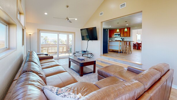 A spacious living room with leather sofas, a flat-screen TV, and a large window. - Views of the Gulf, Ample Parking for Boat and Cars (Port Aransas)