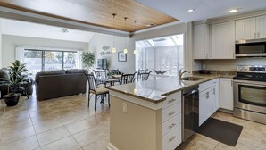 A modern kitchen with a central island, built-in appliances, and a dining area with a view.