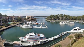 A marina with boats docked, a bridge, and buildings in the background.