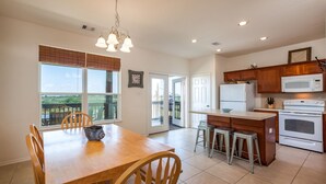 Una cocina amplia con comedor, armarios de madera, microondas, horno y un gran ventanal con vistas panorámicas.