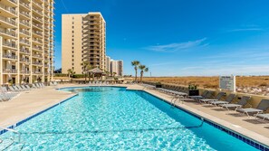 A swimming pool with lounge chairs and a sign indicating pool rules.