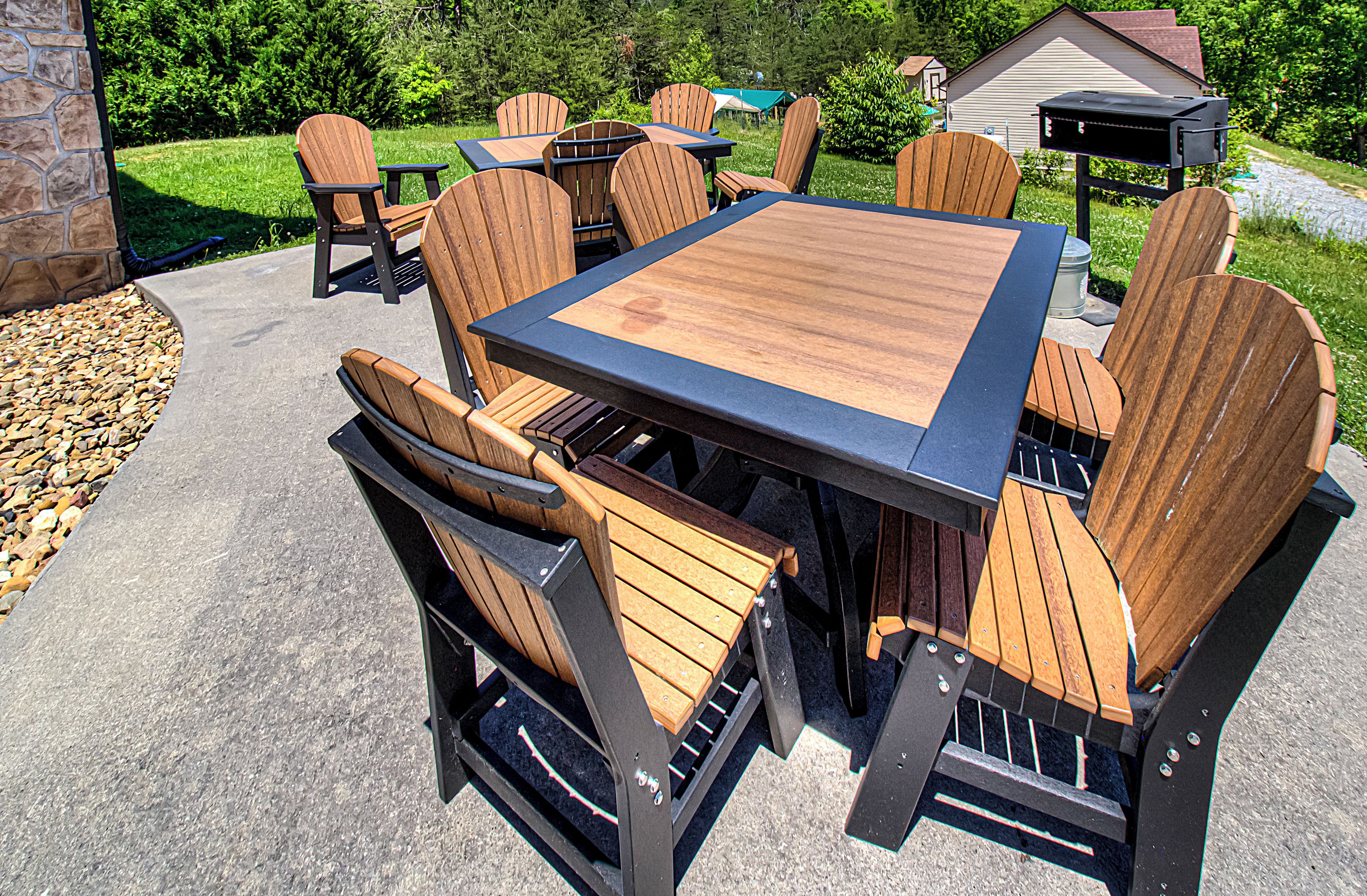 Une terrasse extérieure avec une table et des chaises en bois, un barbecue et un mur en pierre.