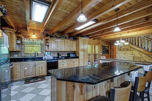 A spacious kitchen with wooden cabinets, a granite countertop, and a large island with seating.