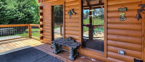 A wooden cabin with a porch, a bench, and a bear decoration.