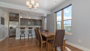 A modern kitchen with a central island, bar stools, and a dining table with chairs. - Best location in Salida! 2 River front decks, looks over Arkansas River waterpark! (Salida)