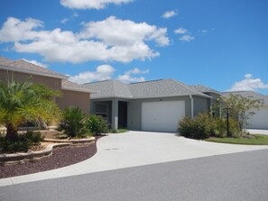 Enjoy a serene home with a covered driveway, landscaped yard, and a palm tree.