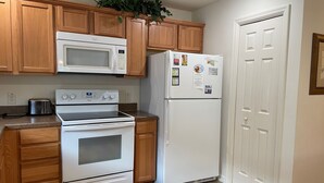 A kitchen with wooden cabinets, a microwave, a refrigerator, a stove, and a toaster. - Your Private Slice of Paradise Near Brownwood! (The Villages)