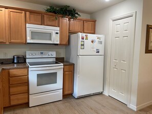 A kitchen with wooden cabinets, a microwave, a refrigerator, a stove, and a toaster. - Your Private Slice of Paradise Near Brownwood! (The Villages)