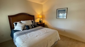 A neatly made bed with a wooden headboard, a bedside table with a lamp, and a framed picture on the wall. - Your Private Slice of Paradise Near Brownwood! (The Villages)