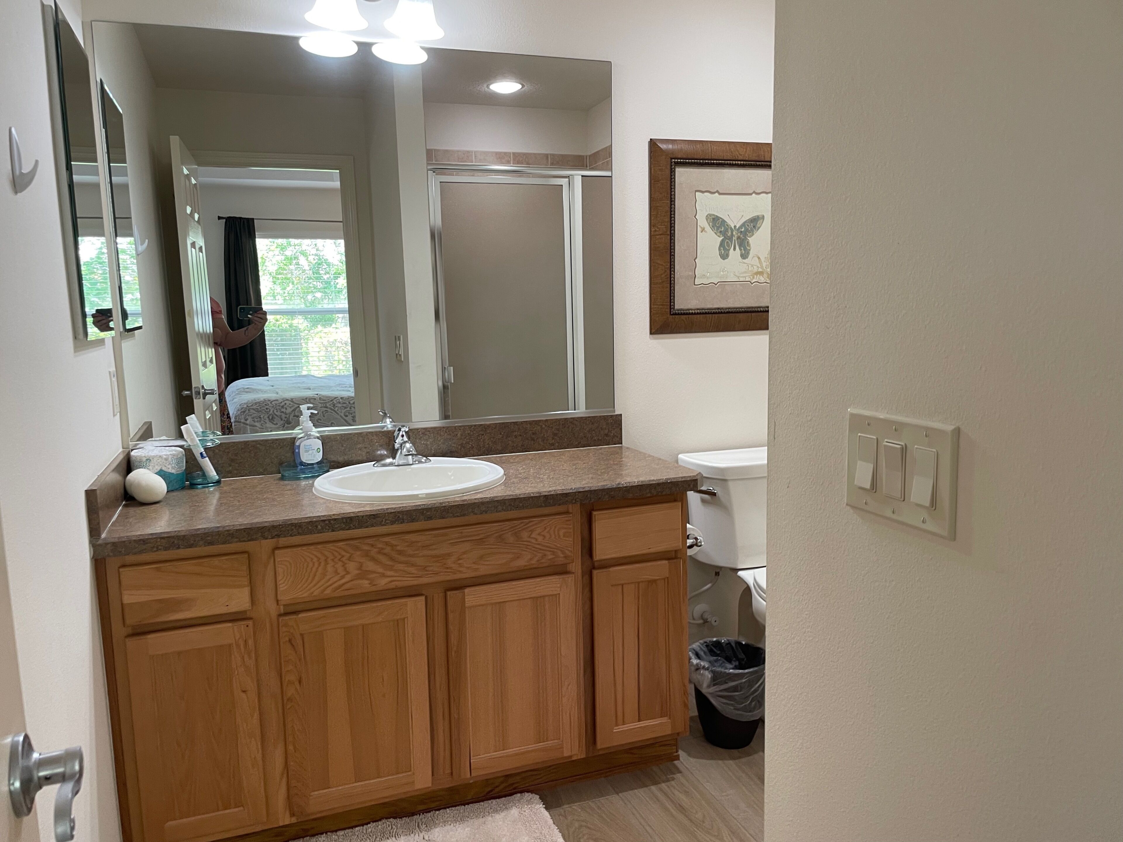 A bathroom with a wooden vanity, a sink, a mirror, and a toilet.