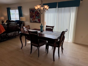 A dining area with a wooden table, chairs, a chandelier, and a painting on the wall.