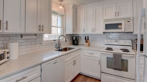 Una cocina moderna con armarios blancos, microondas integrado, estufa y lavabo.
