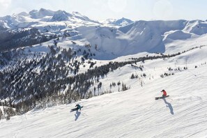 Schneegebirgslage mit Skifahrern, blauem Himmel und Bergen in der Ferne.