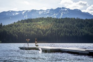 Un muelle se adentra en un lago con montañas al fondo.