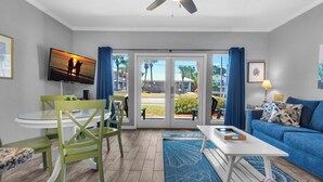 A living room with a TV, green chairs, a blue sofa, and a ceiling fan. - ☀Ground Floor~Walk 2 Beach~Community Pool~1BR+Bunk Caribbean Dunes 120🌴 (Destin)