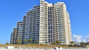 Un hotel moderno de gran altura con múltiples balcones y ubicación frente a la playa.