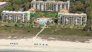 A beachfront hotel with multiple buildings, a swimming pool, and beach umbrellas. - Shorewood 312 -  3 bedroom Beautiful Ocean Front (Hilton Head Island)