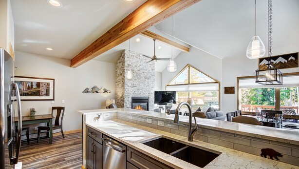 A modern kitchen with a stone backsplash, wooden beams, and a large island with a sink. - RENOVATED! Ski In/Out Townhome Private Hot Tub w/ Panoramic VIEWS! PINE97 (Breckenridge)