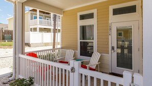 A covered porch with white railings and two Adirondack chairs. - Family & Dog-Friendly Townhome | 2 Heated Pools & Beach Nearby (Corpus Christi)