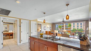 A modern kitchen with a large island, stainless steel appliances, and a view of a building with balconies.