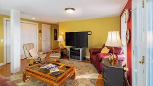 A living room with a sofa, armchair, coffee table, television, and a fireplace.
