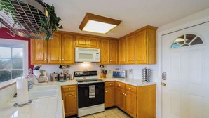 A kitchen with wooden cabinets, a microwave, a stove, and a sink.