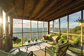 A spacious room with large windows, a wooden ceiling, and a green sofa with cushions. - Lookout Mountain Brow Home.  The Sunset House. (Lookout Mountain)
