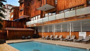 A wooden building with a pool, lounge chairs, and a sign indicating pool rules. - Large Ski-In/Out Lionshead Condo w/ Private Hot Tub and Best Vail Slope Views (Vail)