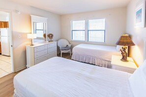 A bedroom with two beds, a dresser, a chair, and a lamp. - Whispering Sands #202 - Small Gulf Front Complex on Dune Allen Beach. (Santa Rosa Beach)