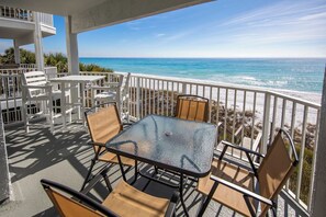A balcony with a glass table and chairs, overlooking a beach and ocean. - Whispering Sands #202 - Small Gulf Front Complex on Dune Allen Beach. (Santa Rosa Beach)