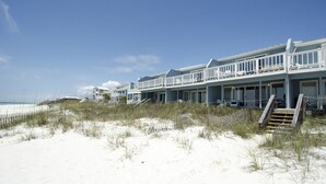 A beachfront hotel with multiple balconies, a sandy beach in front, and a clear sky.
