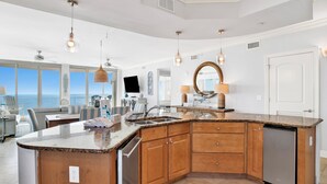 A modern kitchen with a large island, wooden cabinets, and a built-in dishwasher.
